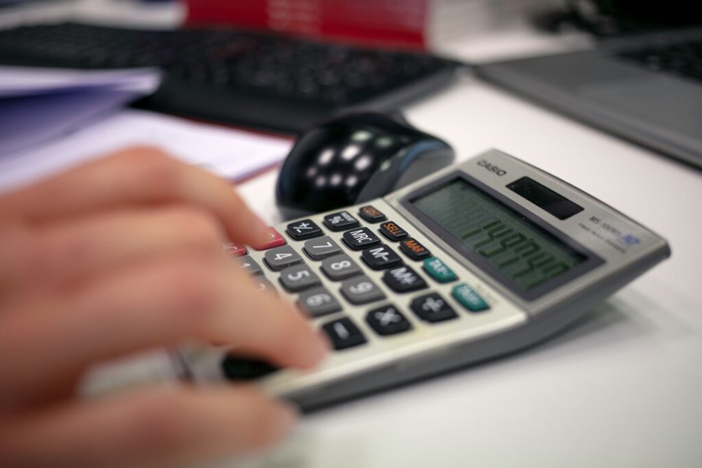Persona calculando la plusvalía municipal con calculadora y escrituras de la vivienda